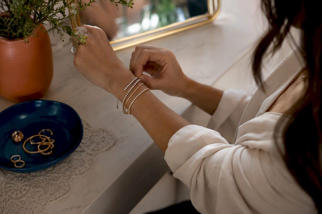 Woman styling layered tennis bracelets on wrist