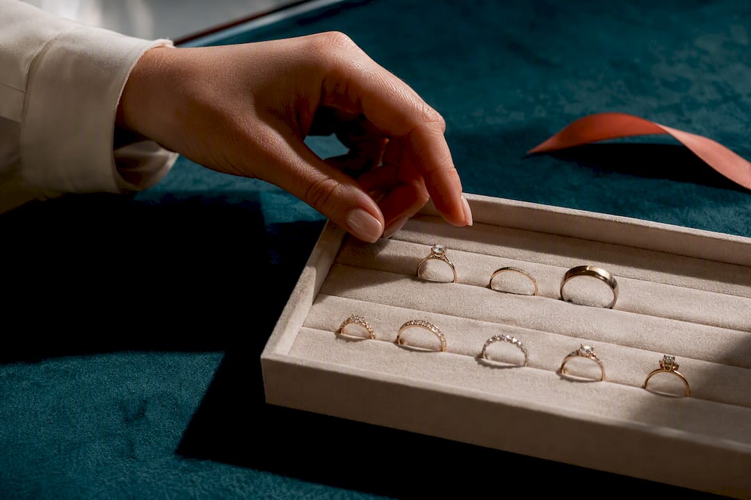 Hand comparing ring styles on jewellery tray